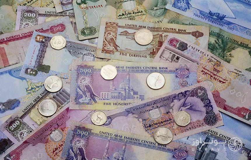 واحد پول دبی؛ تصویری از چند درهم امارات که روی آن‌ها تعدادی سکه قرار دارد.